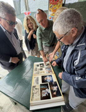 Local woman presenting family album that reveals shared cousins during ancestry reunion in Calabria Italy