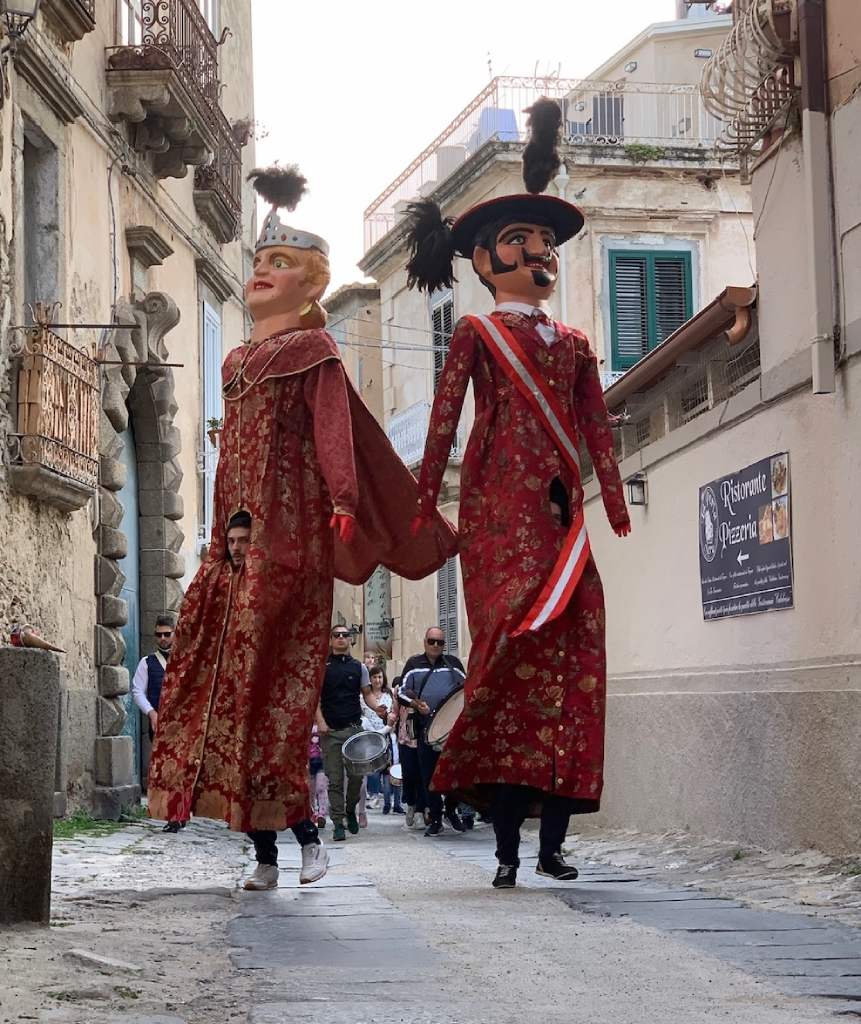 Traditional Giganti papier mache puppets parading through a historic Calabrian street
