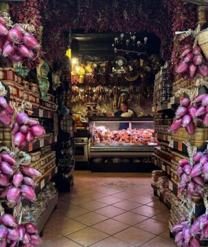 Artisan salumi shopfront in Tropea with hanging cured meats and red onions